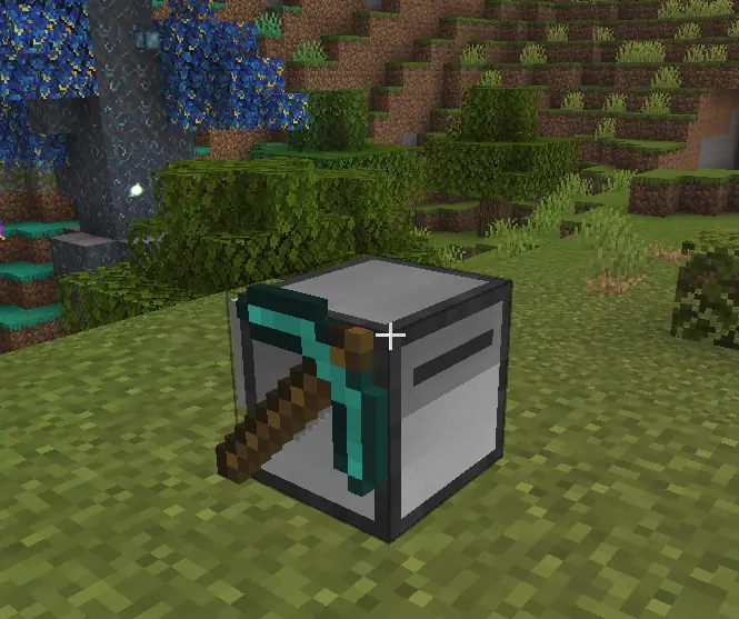 A white automated mining machine with a diamond pickaxe mounted on its side, parked on a grass field in front of a mossy cliff